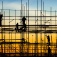 Silhoutettes of workers working on a scaffolding. 