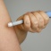 Close view of a person using a weight-loss medication injection pen in their upper arm. 