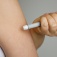 A person injecting a medication into their upper arm. 