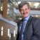 Andrew Talal, MD, is standing in the medical school atrium wearing a jacket and tie. 