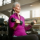 An older woman lifts weights in a gym setting. 