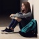 A student sitting alone in a hall with her bookbag. 