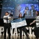 Winners of the 2025 Panasci contest stand together on stage holding an oversize check and a plaque. 