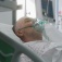 A patient in a hospital bed wearing an oxigen mask. 