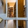 Locked prison cell in the foreground with stacks of books from a library in the background. 