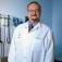 Peter Elkin in white coat standing in exam room. 