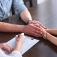 Counselor with patients holding hands across a table. 