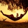 A person reading a book in a hammock on the beach. 