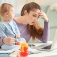 A young mother looks at a computer while holding her baby. 