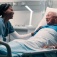Nurse talking with a man in a hospital bed. 