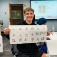 A high school student hods up a shet of Chinese characters they had practiced writing. 