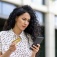 Woman looks at her cell phone while holding a credit card. 