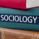 A stack of books, one of which is labeled sociology. 