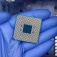 Closeup of a gloved hand holding a semiconductor chip. 