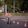 A young child wearing a helmet rides a bike near safety cones. 